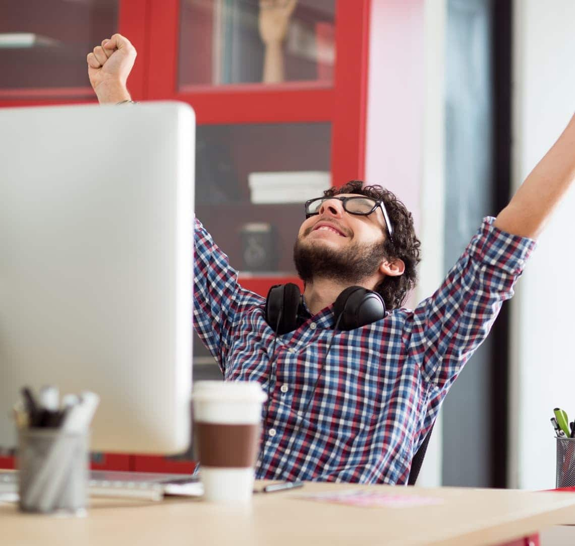 Man happy with hands in the air at computer